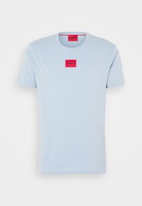 T-shirt bleu clair à manches courtes avec un patch rouge rectangulaire portant le logo "HUGO" centré sur la poitrine et à l'intérieur du col.