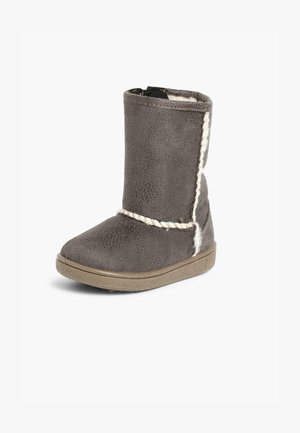 Botín de tobillo de ante gris con un suave forro de tela, que presenta un acento trenzado, suela resistente y un acabado texturizado. Cierre de cremallera lateral.