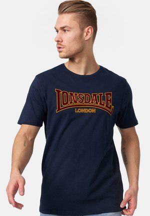 Tamno plava pamučna majica s odvažnim crvenim i žutim grafičkim tiskom "LONSDALE LONDON" na prednjoj strani; kratki rukavi, okrugli izrez.