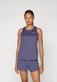 Tank top atlético morado con escote redondeado, combinado con pantalones cortos a juego que cuentan con detalles en verde. Tejido suave y ligero.