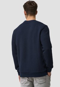 Marineblauwe gestructureerde sweatshirt met een ronde hals, geribbelde boorden en zoom; heeft een bubbelpatroon op de stof.