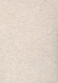 Helles beige ärmelloses Oberteil aus geripptem Stoff, mit rundem Ausschnitt und subtiler Textur, die schwache graue Muster aufweist.