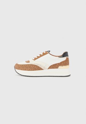 Sneaker à plateforme basse avec tissu marron à motifs, panneaux en cuir blanc, accent doré au talon et lacets blancs sur fond gris.