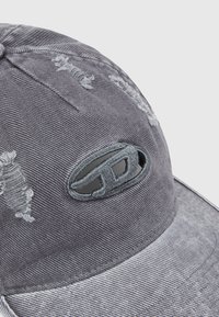 Casquette en denim gris vieilli avec une visière incurvée et un logo brodé. Présente des accents effilochés et un tissu texturé.