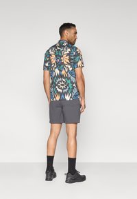 Πουκάμισο με κοντό μανίκι, πολύχρωμο μοτίβο σε σκούρο φόντο. Συνδυασμένο με γκρι σορτς και μαύρα παπούτσια. Ομαλή υφή και άνετη εφαρμογή.