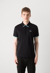 Czarna koszulka polo z kontrastującym turkusowym kołnierzykiem i mankietami. Posiada zapięcie na trzy guziki oraz małe logo na piersi.