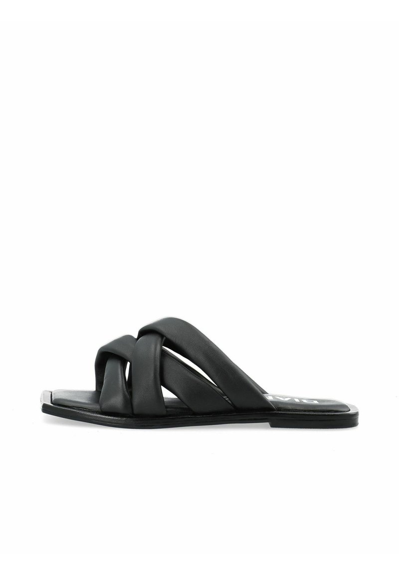 Sandalo scivoloso in pelle nera con fascette incrociate, suola piatta e design minimalista. Texture liscia con una leggera lucentezza.