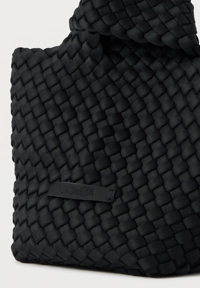 Μαύρη υφασμάτινη τσάντα με υφή, με περίτεχνο πλεκτό σχέδιο και διακριτική ετικέτα με ανάγλυφο κείμενο.