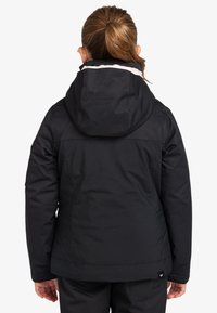 Schwarze isolierte Jacke mit Kapuze, die eine glatte Textur, ein Logo-Patch auf dem Rücken und ein klares, maßgeschneidertes Design aufweist.