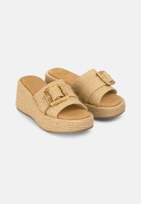 Sandali platform intrecciati beige con suola spessa, dotati di una fascia larga e di un grande dettaglio a fibbia quadrata. Soletta in pelle liscia.