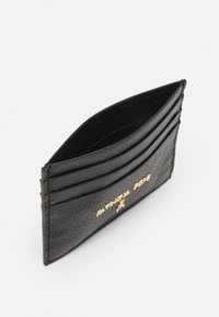 Portafoglio in pelle nera con superficie testurizzata, quattro scomparti per carte e un accento in oro del logo sul davanti. Design compatto e minimalista.
