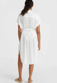 White, lightweight shirt dress with a gathered back, side slits, and a tie at the neck, featuring a slightly sheer fabric and relaxed fit.