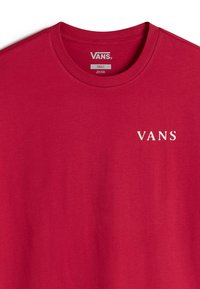 Červené tričko s krátkým rukávem vyrobené z bavlny s kulatým výstřihem. Na levé hrudi se nachází bílé logo "VANS". Hladká textura, jednoduchý design.