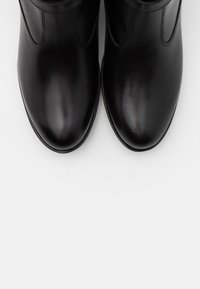 Czarne skórzane botki za kostkę o gładkim wykończeniu, okrągłym nosku, minimalnym przeszyciu i krótkiej elastycznej wstawce z boku, co ułatwia zakładanie.