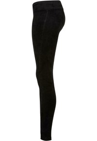 Czarne legginsy mają żebrowaną fakturę, dopasowany krój i szeroki pas. Projekt jest minimalistyczny, bez widocznego logotypu czy wzorów.