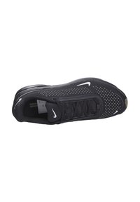Zapatilla deportiva negra con parte superior de malla texturizada, que presenta perforaciones blancas, cordones y un acento del logo de Nike en blanco contrastante.