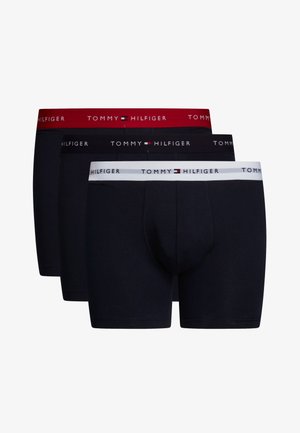 Três pares de cuecas boxers para homens em cores escuras. Características incluem cinturas elásticas: vermelha, preta e branca, com o logótipo "TOMMY HILFIGER" em texto contrastante.