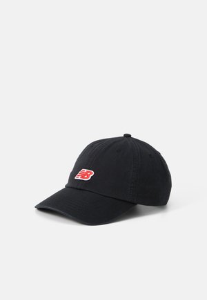 Gorra de algodón negra con visera curvada, que presenta un pequeño logotipo rojo y blanco de New Balance en la parte frontal. Diseño simple con seis ojales de ventilación.