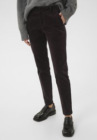 Viskoosihousut tumman burgundin värissä, slim fit -mallilla. Ominaisuuksiin kuuluu etupockets ja sileä pinta, yhdistettynä mustiin loafer-kengiin.
