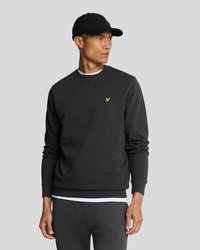 Black sweatshirt made of cotton blend, features ribbed cuffs and hem, with a small yellow logo on the chest. Worn with a black cap.