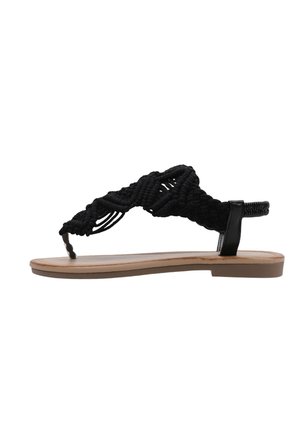 Sandalia plana con suela color canela y tiras trenzadas negras, con una lazada para el dedo y una correa en el tobillo para mayor soporte.