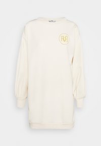 Kreemivärviline ülerõhku sweatshirt, millel on õhupallina varrukad, soonikute mansetid ja ümar kollane tikandiga logo rinnal.