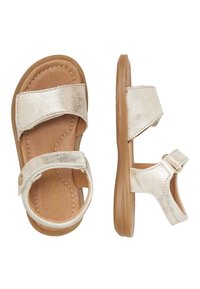 Sandali metallici oro con due fasce larghe, chiusura alla caviglia regolabile e soletta testurizzata. Suola marrone soft. Design piatto.