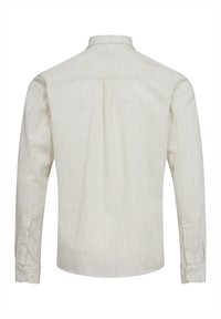 Camicia a maniche lunghe di colore chiaro realizzata in tessuto testurizzato, con colletto a punte, yoke posteriore e polsini con bottoni. Design semplice e minimalista.