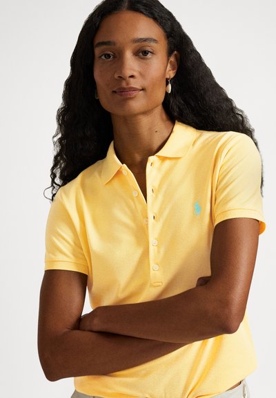 Žlté polokošeľa s textúrovanou látkou, štvorradovým gombíkovým zapínaním a malým tyrkysovým logom na ľavej strane hrude. Krátke rukávy a klasický strih.