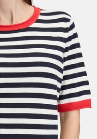 Stripet t-shirt med marineblå og hvide striber, rød ribbet krave og ærmer, korte ærmer, blødt stof.