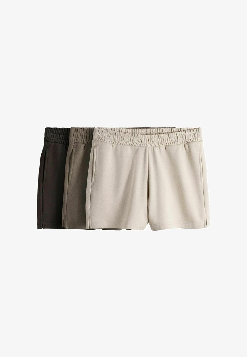 Trois paires de shorts décontractés à taille élastique en crème, taupe et brun foncé, disposées côte à côte sur un fond blanc.