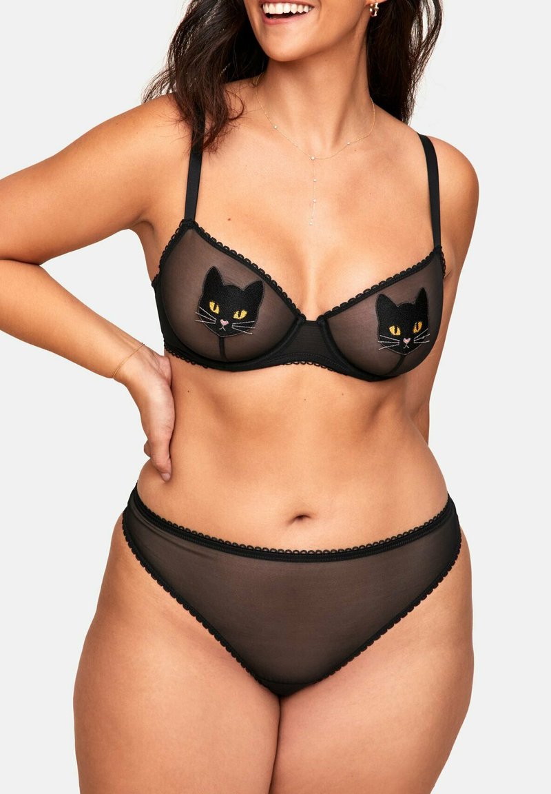 Ensemble de lingerie en mesh noir comprenant un bralette orné de visages de chat noirs brodés, un soutien-gorge assorti en dentelle noire, ainsi que des bretelles réglables.