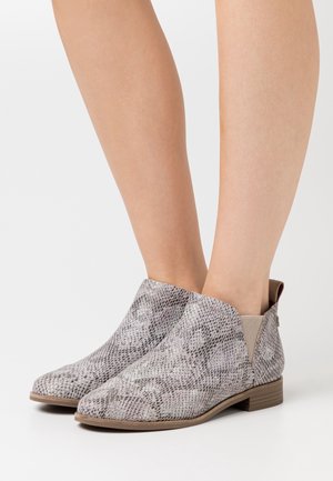 Bottines à motif serpent gris avec un petit talon block et des panneaux latéraux en élasthanne. Texture lisse avec un bout arrondi.