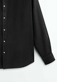 Zwarte langemouwige shirt gemaakt van gladde stof, met een knoopsluiting aan de voorkant, een ronde zoom en zichtbare knoopdetails.