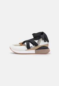 Bílé a černé sportovní boty s leopardím vzorem, které mají texturovanou podrážku, pletené detaily a černé saténové stužky pro zapínání.