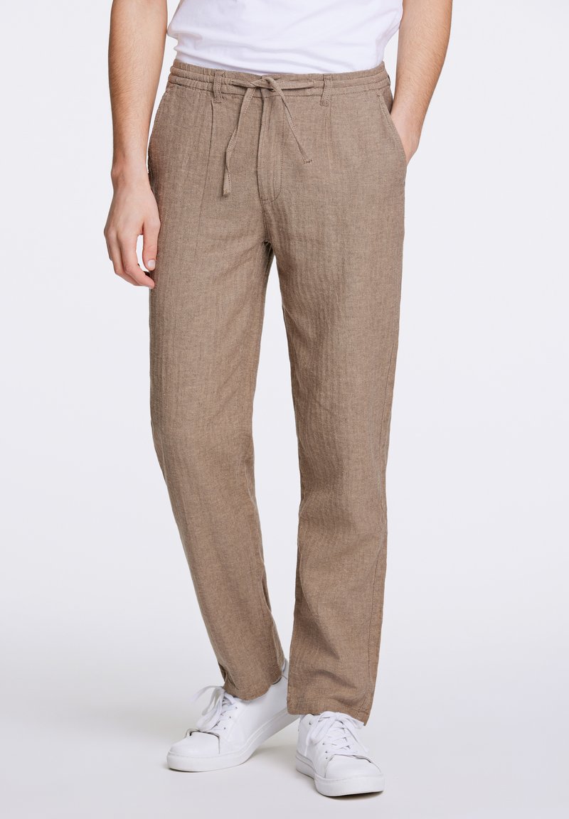 Lichtbruine, ademende linnen broek met een elastische tailleband en koord. Beschikt over zijzakken en een gestructureerd geweven patroon.
