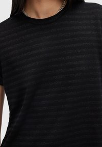 Camiseta negra con rayas texturizadas horizontales, con un escote redondo y mangas cortas, hecha de una tela suave y ligera.