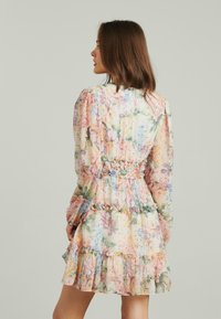 Blumengemustertes Kleid mit langen Puffärmeln, tailliertem Schnitt und Rüschensaum. Die Farben umfassen Pastellrosa, Blau und Grün auf einem hellen Hintergrund.