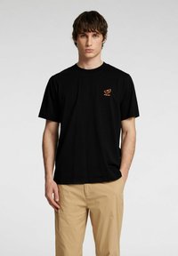 Svart bomullströja med en liten orange grafisk design på bröstet. Korta ärmar och rundad halsringning.