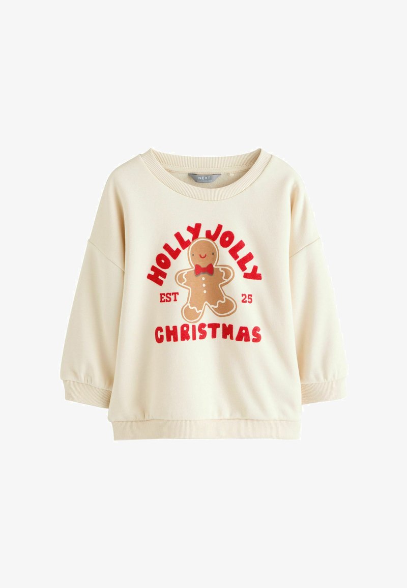 Sweatshirt couleur crème avec un col rond, des manches longues et un graphique ludique représentant un bonhomme en pain d'épice. Présente le texte rouge "NOËL JOYEUX".