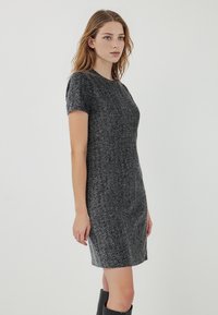 Abito grigio a maniche corte in tessuto texturizzato, con una silhouette aderente che arriva sopra il ginocchio. Decorato con motivi sottili.