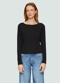 Schwarzes Langarmshirt mit Rundhalsausschnitt, aus weichem Stoff. Kombiniert mit hellblauen, hoch taillierten, weit geschnittenen Jeans.