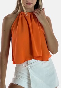 Oranje haltertop met geplooide stof en een geraffineerde halslijn, gecombineerd met witte shorts met een gevouwen voorkant en rafelige zoom.