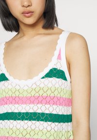 Camisola de malha com um decote arredondado em formato de ondas, com padrões listrados em verde, rosa e branco numa textura rendada.