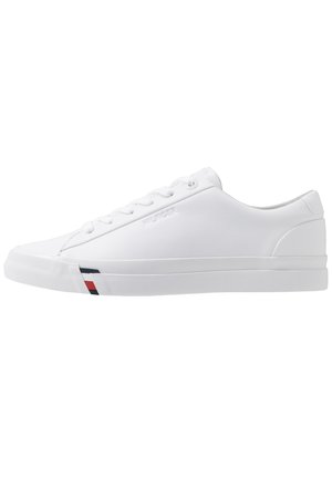 Hvid lav snøresneaker med glat læderoverdel og små røde og blå striber nær sålen på forsiden af den ydre side.