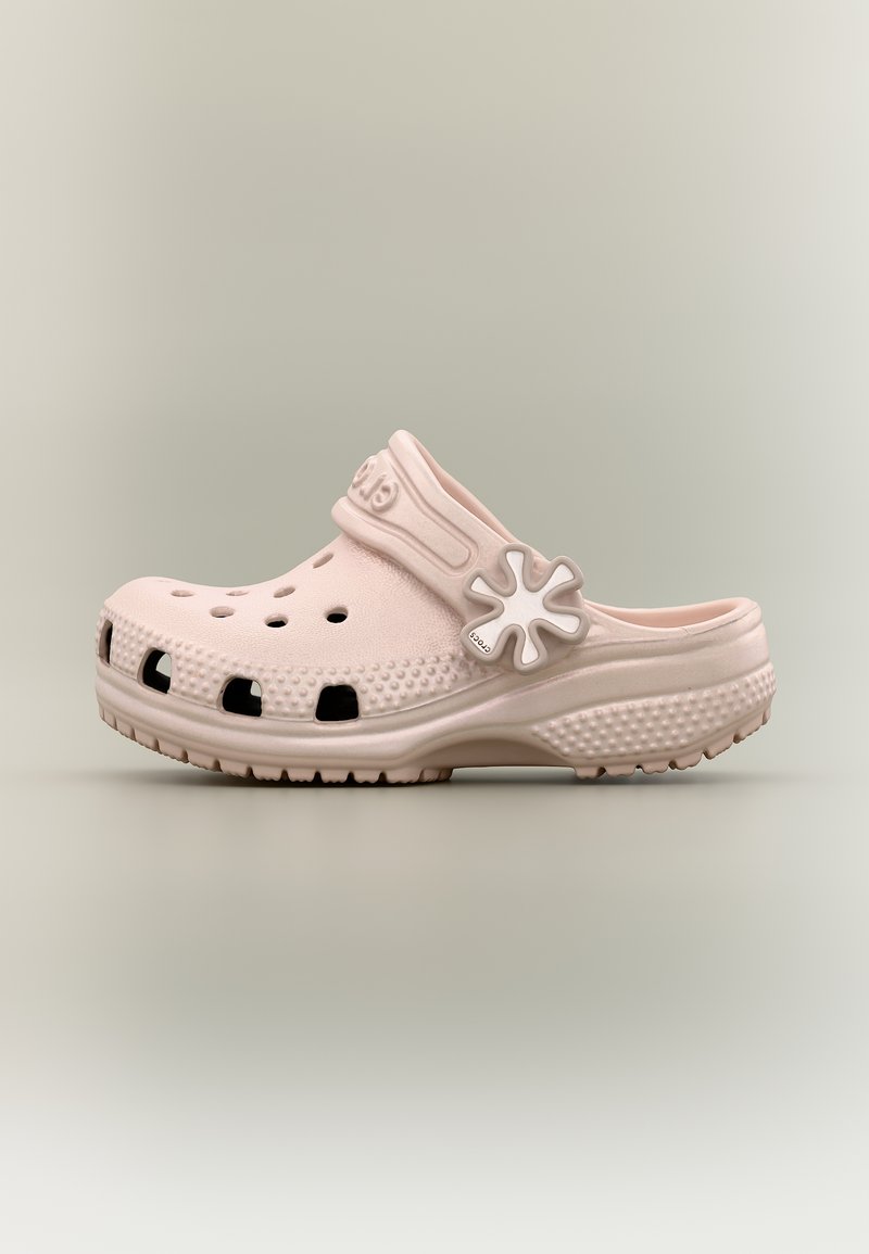 Ροζ ανοιχτό παντόφλα με τρύπες αερισμού, υφή στη σόλα και ρυθμιζόμενο λουράκι με κούμπωμα σε σχήμα λουλουδιού σε ουδέτερο φόντο.