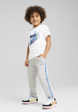 Camiseta blanca con un gráfico de un coche azul, pantalones de chándal grises con franjas laterales azules, y zapatillas negras, blancas y amarillas.