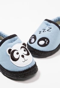 Modré plátěné nazouvací boty s černými detaily. Levá bota má na sobě panda obličej; pravá bota zobrazuje kreslené oči a detaily textu "zzz". Černé podrážky.