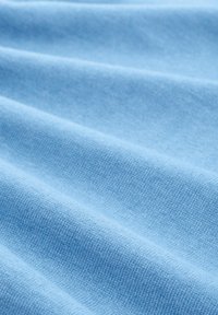 Jasnoniebieska tkanina o gładkiej fakturze, z delikatnymi fałdami i subtelnym wzorem splotu. Materiał wydaje się lekki i przewiewny.