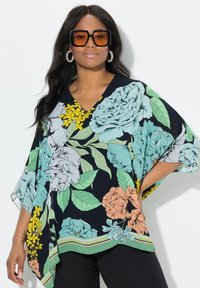 Blusa floreale nera con grandi motivi di fiori blu, rosa e gialli. Design a V, maniche ampie e un orlo a strisce multicolori.